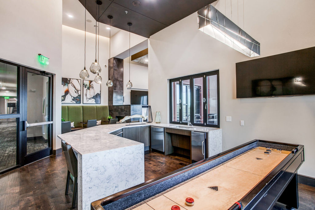 Clubhouse area with large countertop and seating and shuffleboard