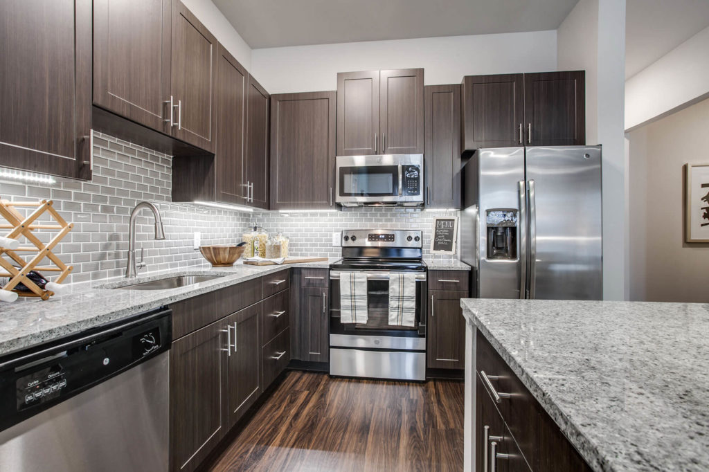 Kitchen with wood-style floors, stainless-steel appliances, granite counters, and stainless single basin sink
