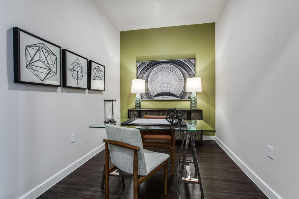 Office nook with wood-style floors, desk with chair, accent wall, and cabinet