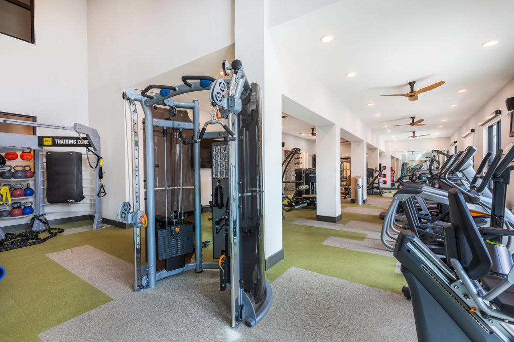 Fitness center with cardio machines, weight machine, kettlebells and ceiling fans