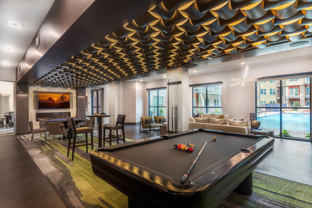 Clubhouse with fireplace, decorative ceiling, pool table, and variety of seating overlooking pool area