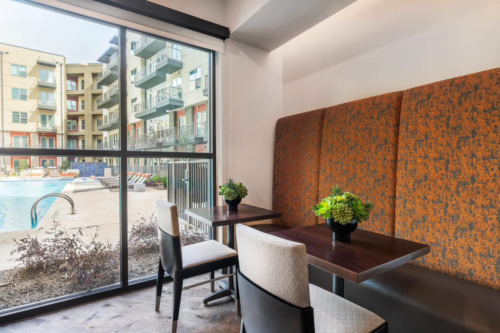 Seating area with booth, chairs, and table overlooking the pool area