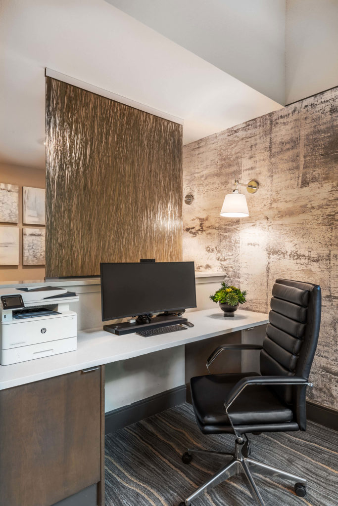 Office space with computer, rolling desk chair, printer, accent wall, and privacy divider