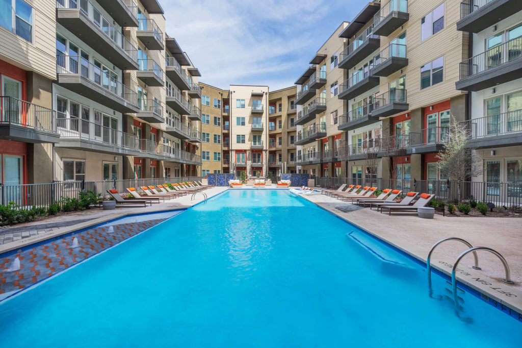 Resort-like pool with lounge chairs, safety railing, and small decorative fountains