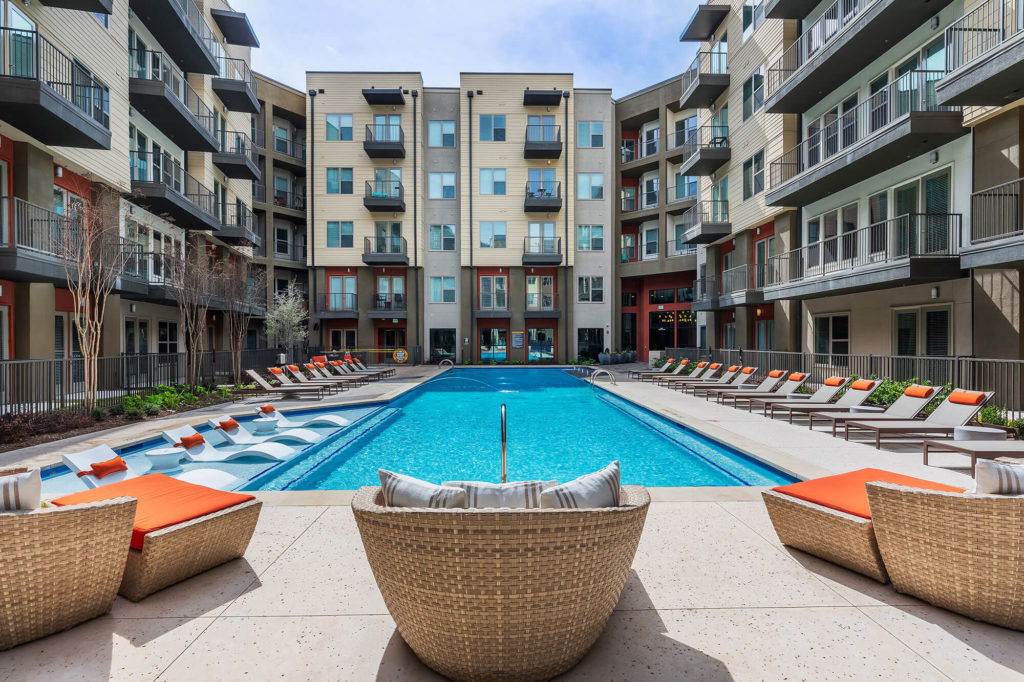 Resort-like pool with in-water seating, lounge chairs, plush seating, and safety gate