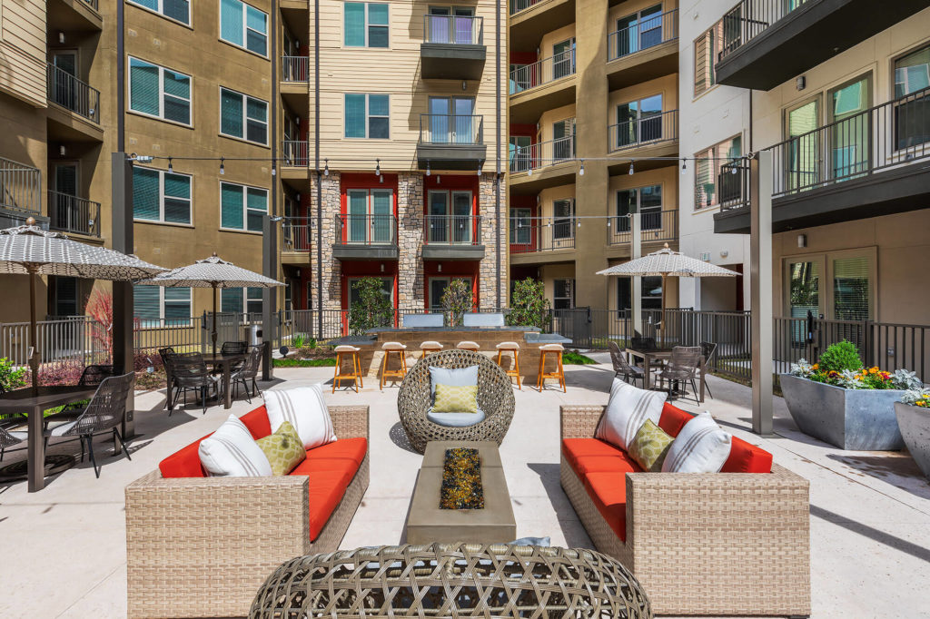 Outdoor courtyard area with variety of seating, umbrellas, and decorative landscaping