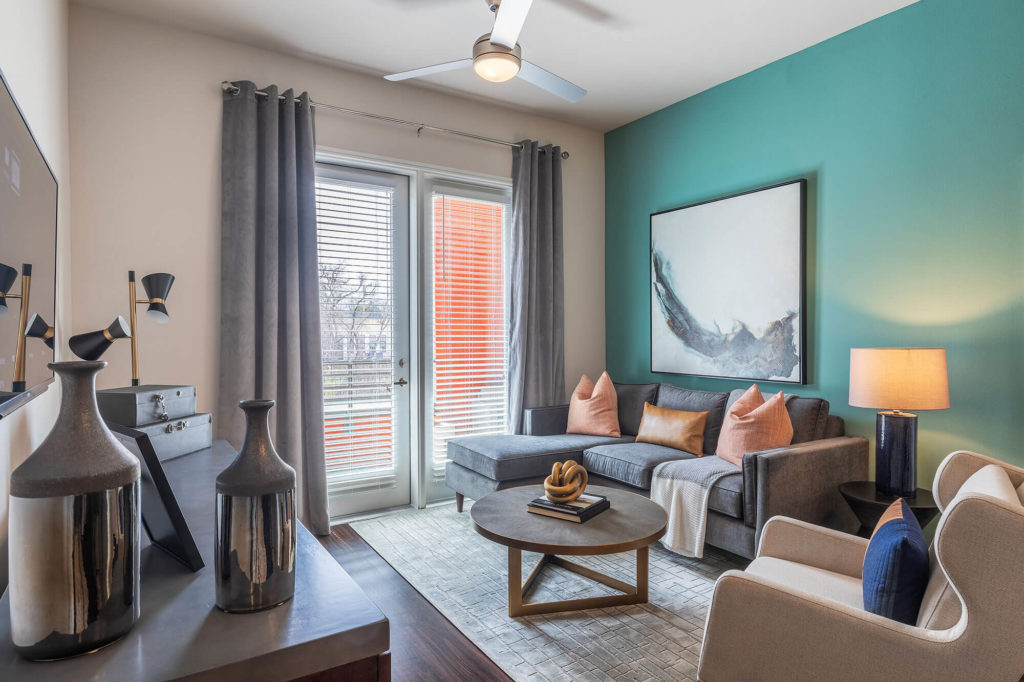 Living room with wood-style floors, ceiling fan, door leading to patio and modern furniture